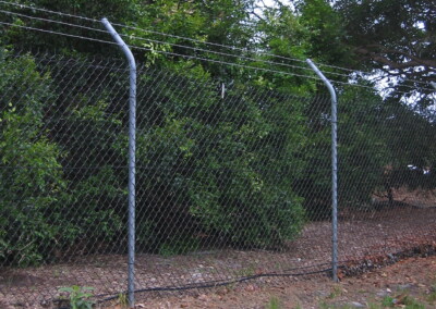 Chainwire fencing with cranked (bent) posts for barbed wire