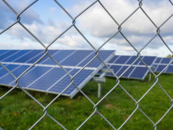 Solar,Panel,Or,Photovoltaic,Farm,Behind,Metal,Chainlink,Fence,On