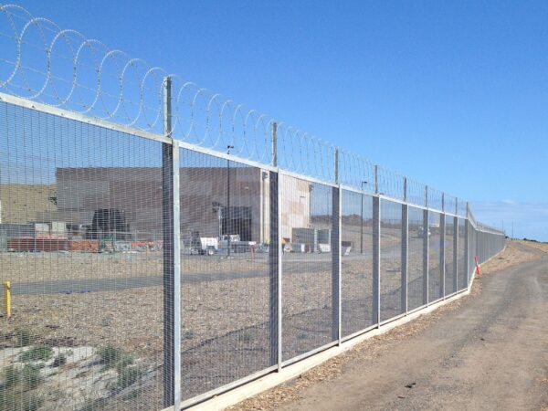 Flat loop razor wire layered with barbed wire rows on fence